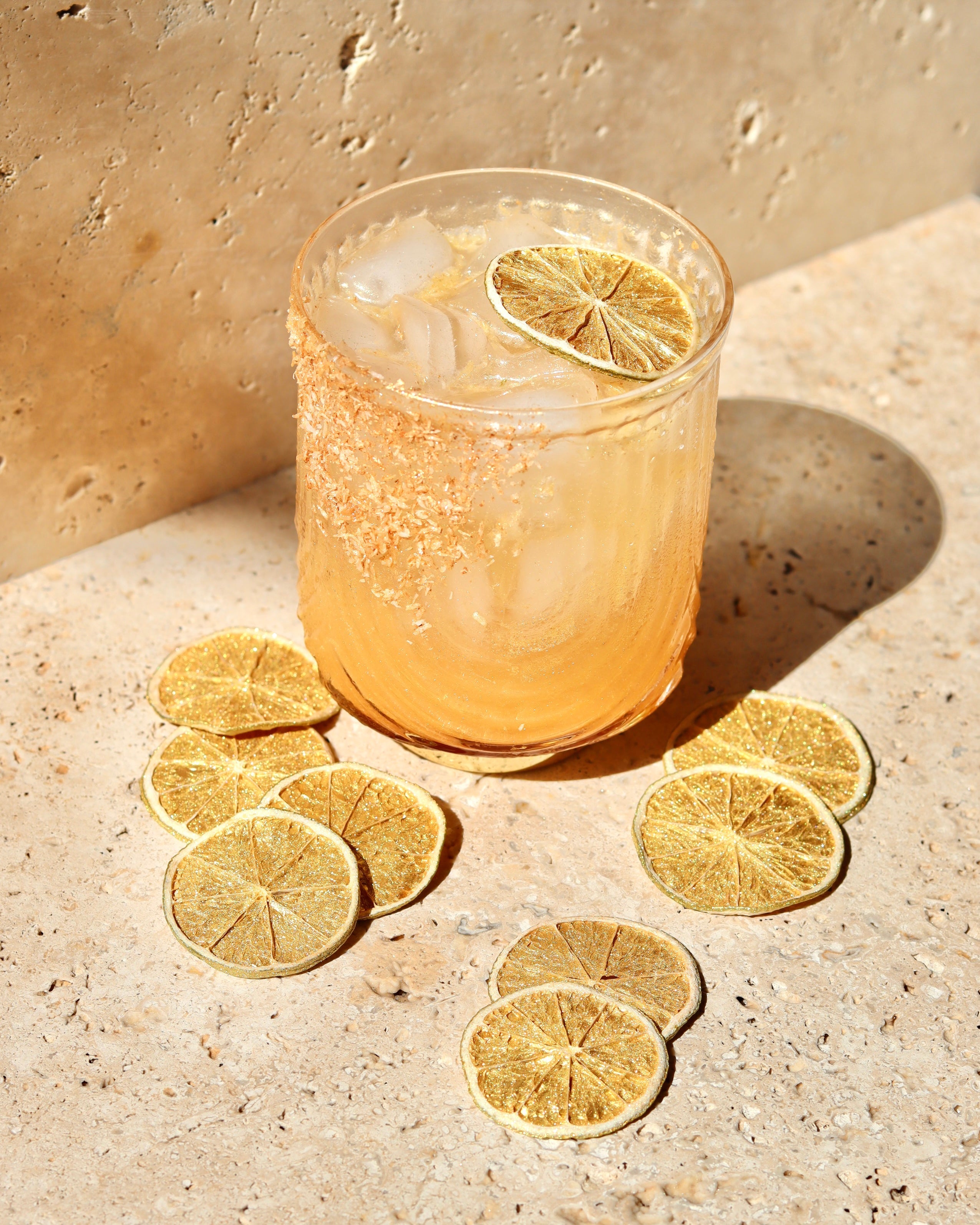 Glass of iced drink with lime slices on a stone surface