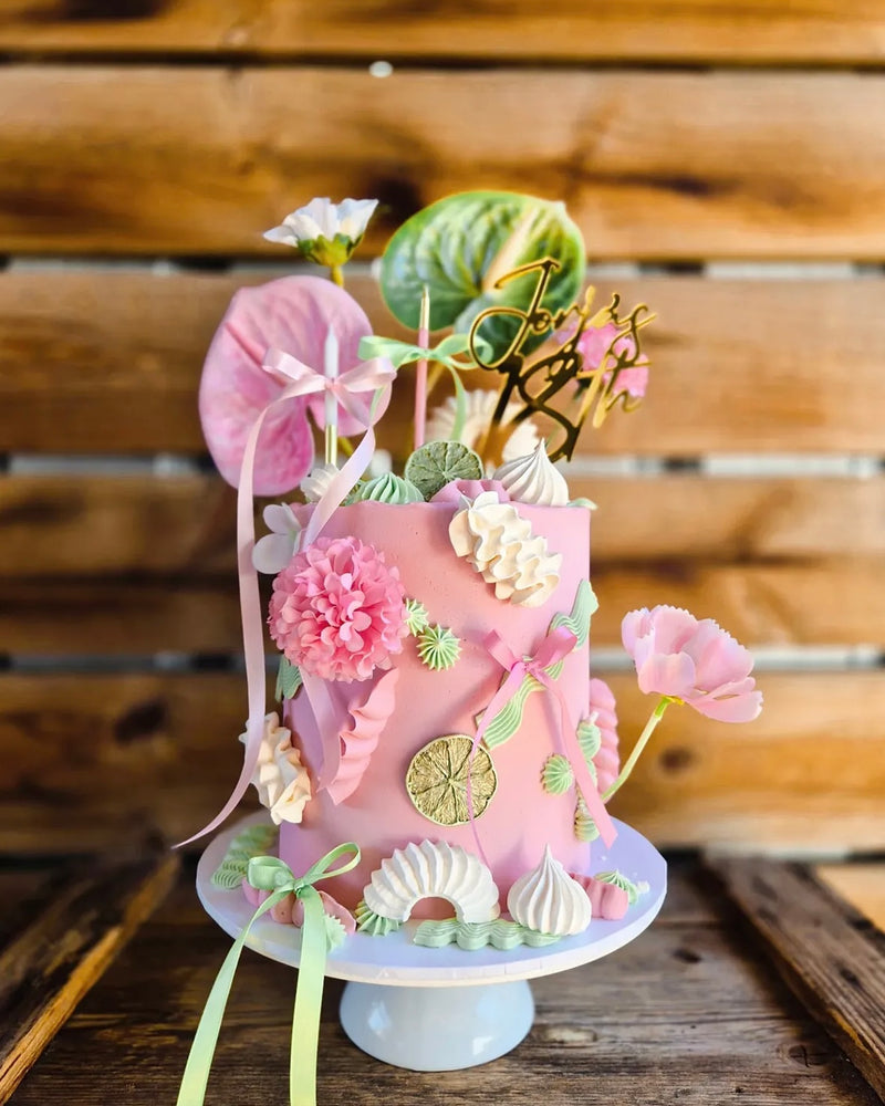 Decorative cake with pink and green floral designs and dried lime wheels