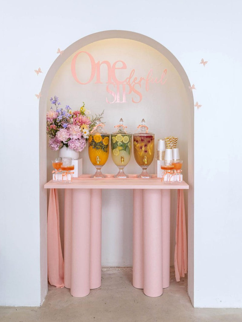 Decorative setup with drinks and flowers inside an archway with mocktails